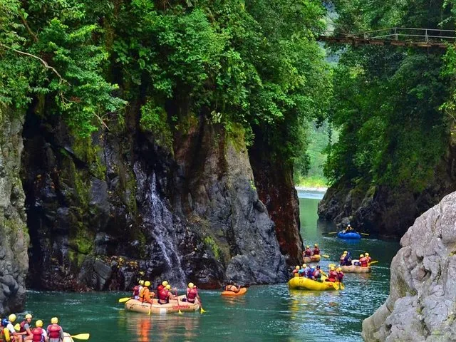 Groupe d'excursion de rafting naviguant dans une gorge aux parois rocheuses et à la verdure